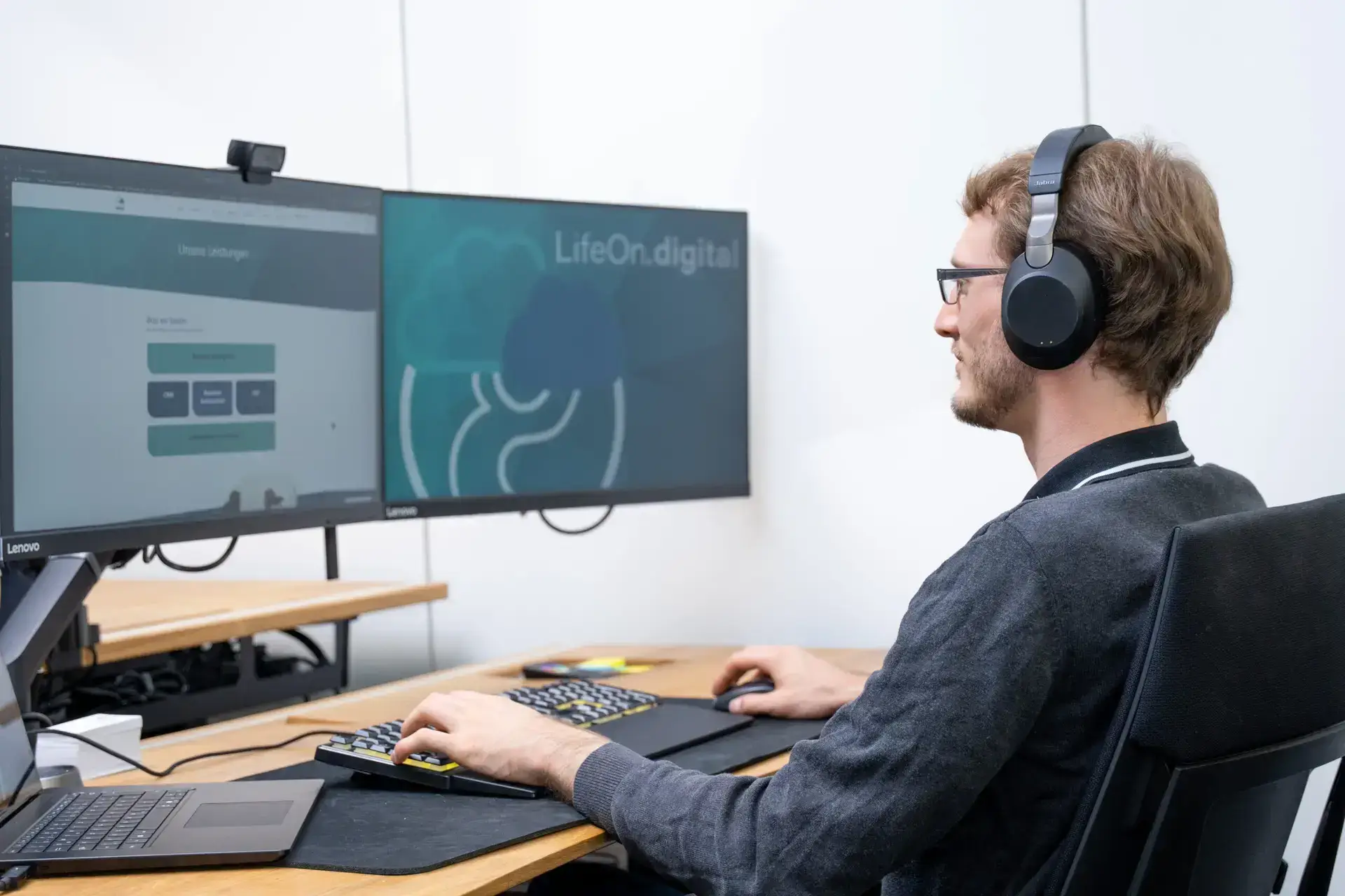 Ein LifeOn.digital Mitarbeiter trägt ein Headset, bedient einen Computer und führt eine IT-Betreuung durch.