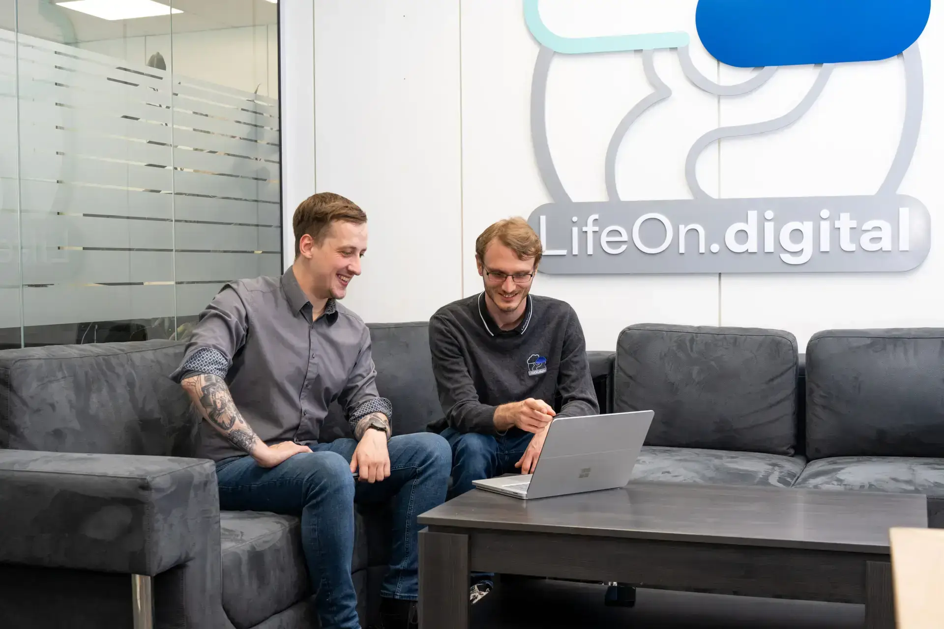 Zwei LifeOn.digital Mitarbeiter schauen gemeinsam auf einen Laptopbildschirm und geben eine Copilot-Schulung.